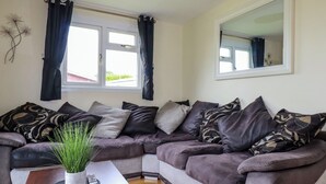 Un salon avec un canapé d’angle, une table basse et une plante en pot.