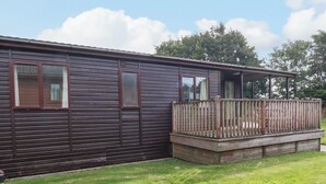 Een laag gebouwd houten huis met een omheind terras en een gazon.