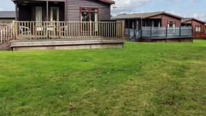 Een houten hutje met een veranda, een omheinde tuin en een heldere lucht.