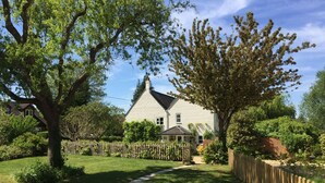 Une maison avec un chemin pavé menant à la porte d’entrée, entourée d’une clôture en bois et d’une végétation luxuriante.