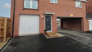 Ein zweistöckiges Backsteinhhaus mit einer weißen Garagentür, einer kleinen Veranda und einer Auffahrt zur Garage.