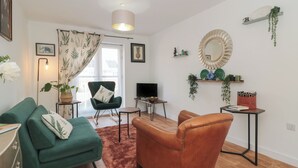 Ein modernes Wohnzimmer mit einem grünen Sofa, einem braunen Ledersessel, einem Fernseher und einem Kamin.