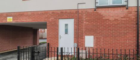 A residential building with a red brick facade, a white door, and a small window.