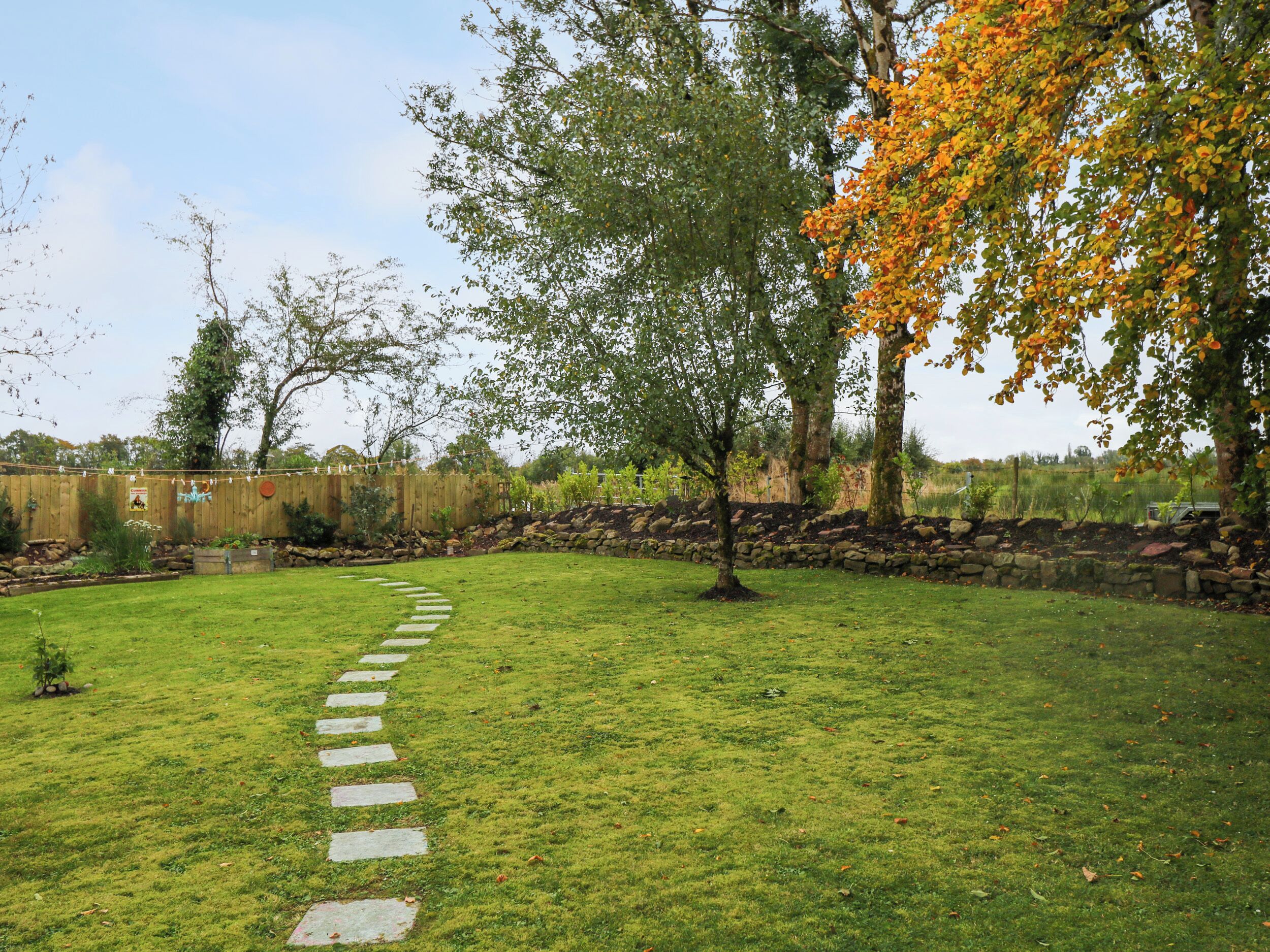Un jardin avec un chemin de pierres menant à une terrasse en bois.