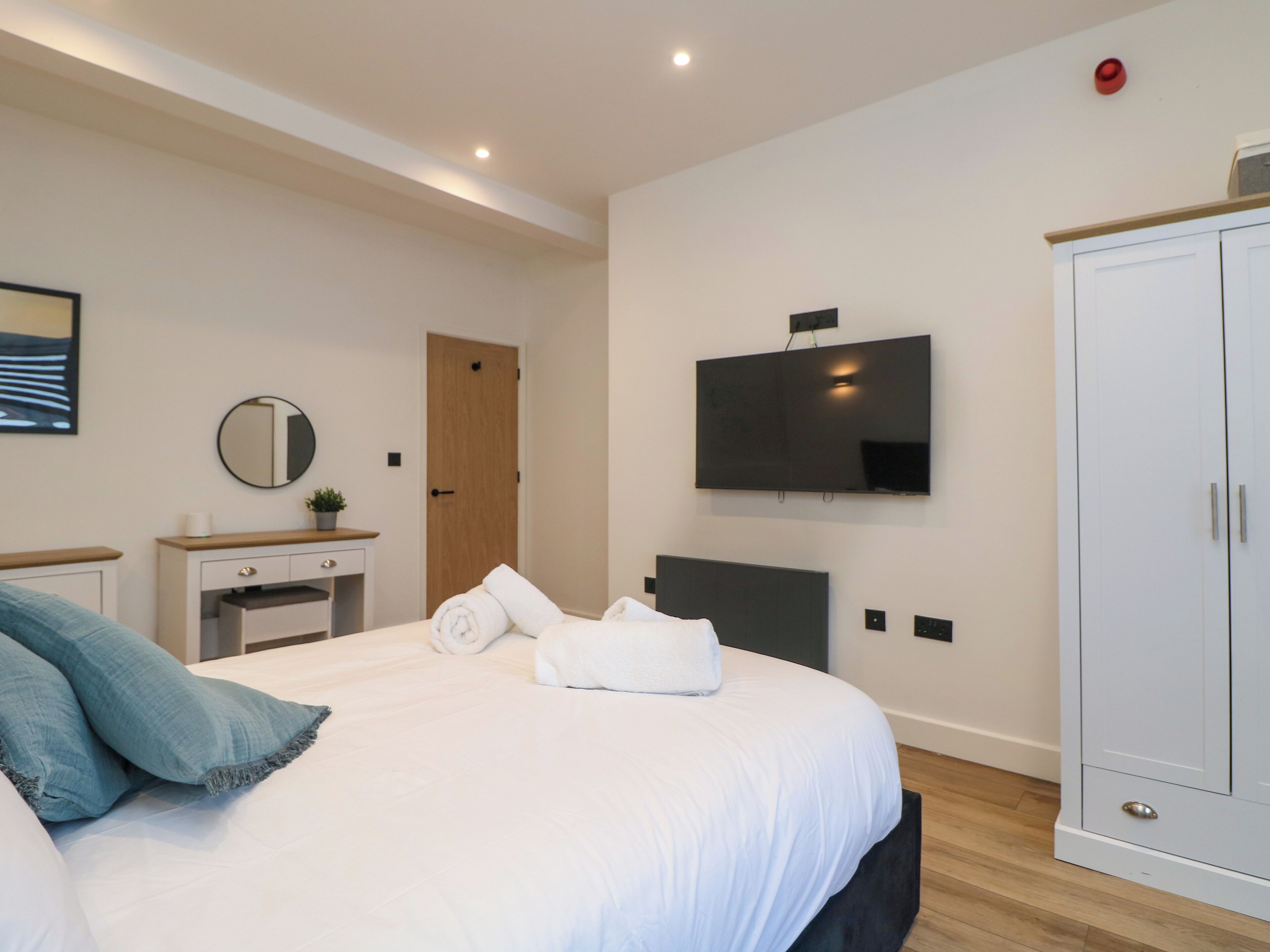 A modern bedroom with a bed, a dresser, a television, and a wardrobe.