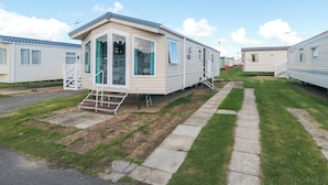 A row of mobile homes with a grassy lawn and a paved walkway. - 13 Gosling (Scarborough)