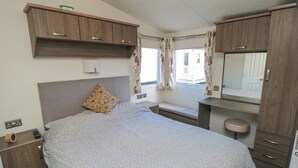 A bedroom with a bed, a nightstand, a dresser, a window with curtains, and a mirror. - 13 Gosling (Scarborough)