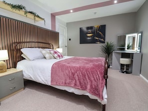 A neatly arranged bedroom with a bed, bedside table, and a mirror. - Steam and Stay @ Hoole (Chester)