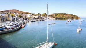 Un port où de nombreux voiliers sont amarrés au quai, entouré de bâtiments et avec des collines en arrière-plan.