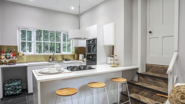 Une cuisine moderne dotée d’un îlot central, de tabourets de bar et offrant une vue sur l’extérieur.