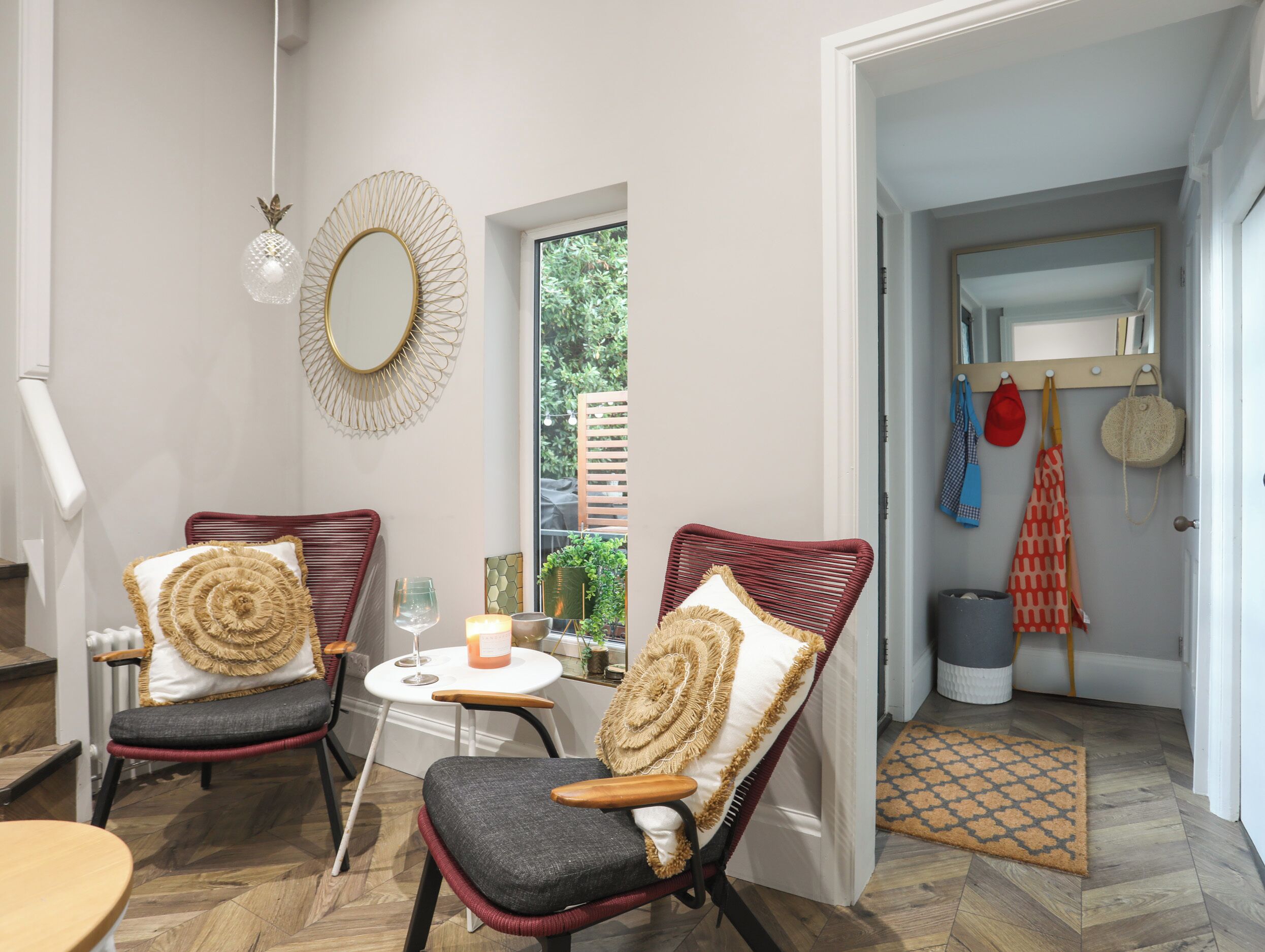 Una habitación acogedora con dos sillones de mimbre, una mesita con una vela y un espejo en la pared.