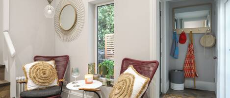 Una habitación acogedora con dos sillones de mimbre, una mesita con una vela y un espejo en la pared.