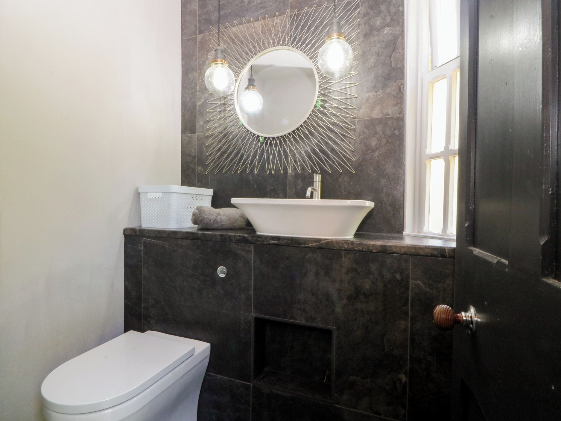 Ein Badezimmer mit einer weißen Toilette, einem Waschbecken mit Spiegel darüber und einem Handtuch auf der Ablagefläche.