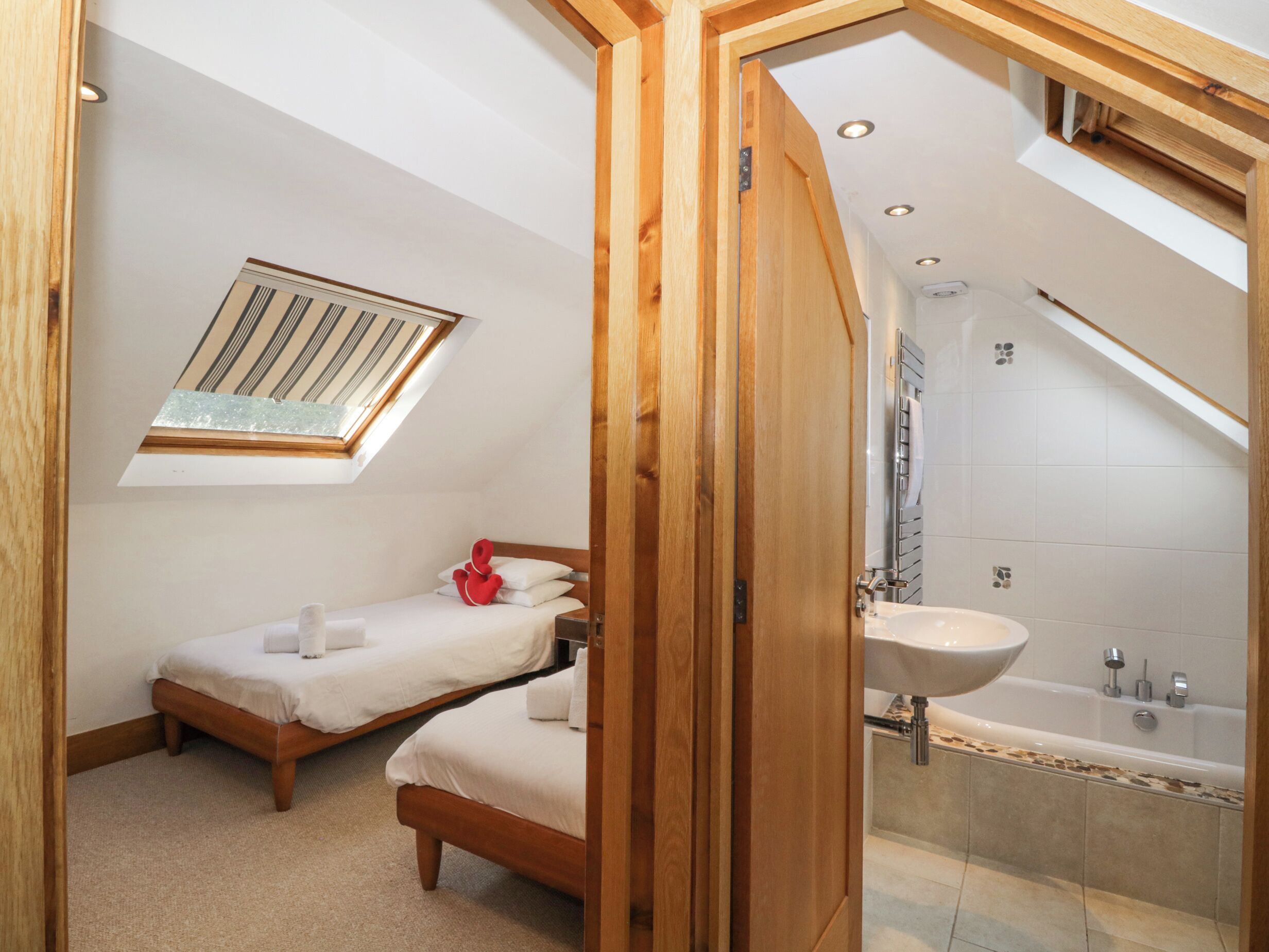 A bedroom with two beds, a skylight, a bathroom with a bathtub, and a shower.