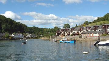 A coastal village with houses along the water, boats docked, and a clear sky.
