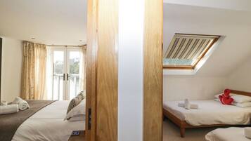 A hotel room with two beds, a skylight, a balcony with curtains, and a view of the outside.