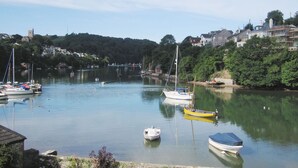 A calm harbor with several boats docked, surrounded by lush greenery and residential buildings.