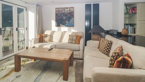 A modern living room with a sofa, a coffee table, a bookshelf, and a painting on the wall.