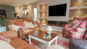 A cozy living room with a fireplace, a television, and comfortable seating. - Little Willesleigh (Barnstaple)