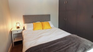 Een slaapkamer met een bed, nachtkastje en kledingkast.
