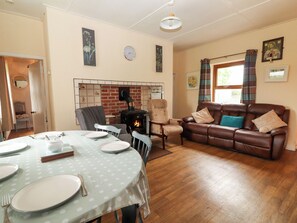 Ein gemütliches Wohnzimmer mit Kamin, einem Essbereich mit Tisch für vier Personen und einer bequemen Couch.