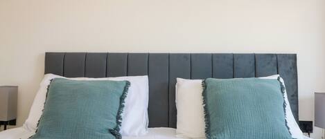 A bed with two pillows, a grey headboard, and a wall decoration.