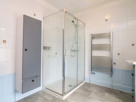Un baño moderno con ducha de vidrio, inodoro integrado y un perchero para toallas.
