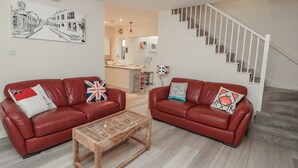 A living room with two red leather sofas, a glass-top coffee table, and a staircase leading to an upper floor. - Full Deck (Dartmouth)