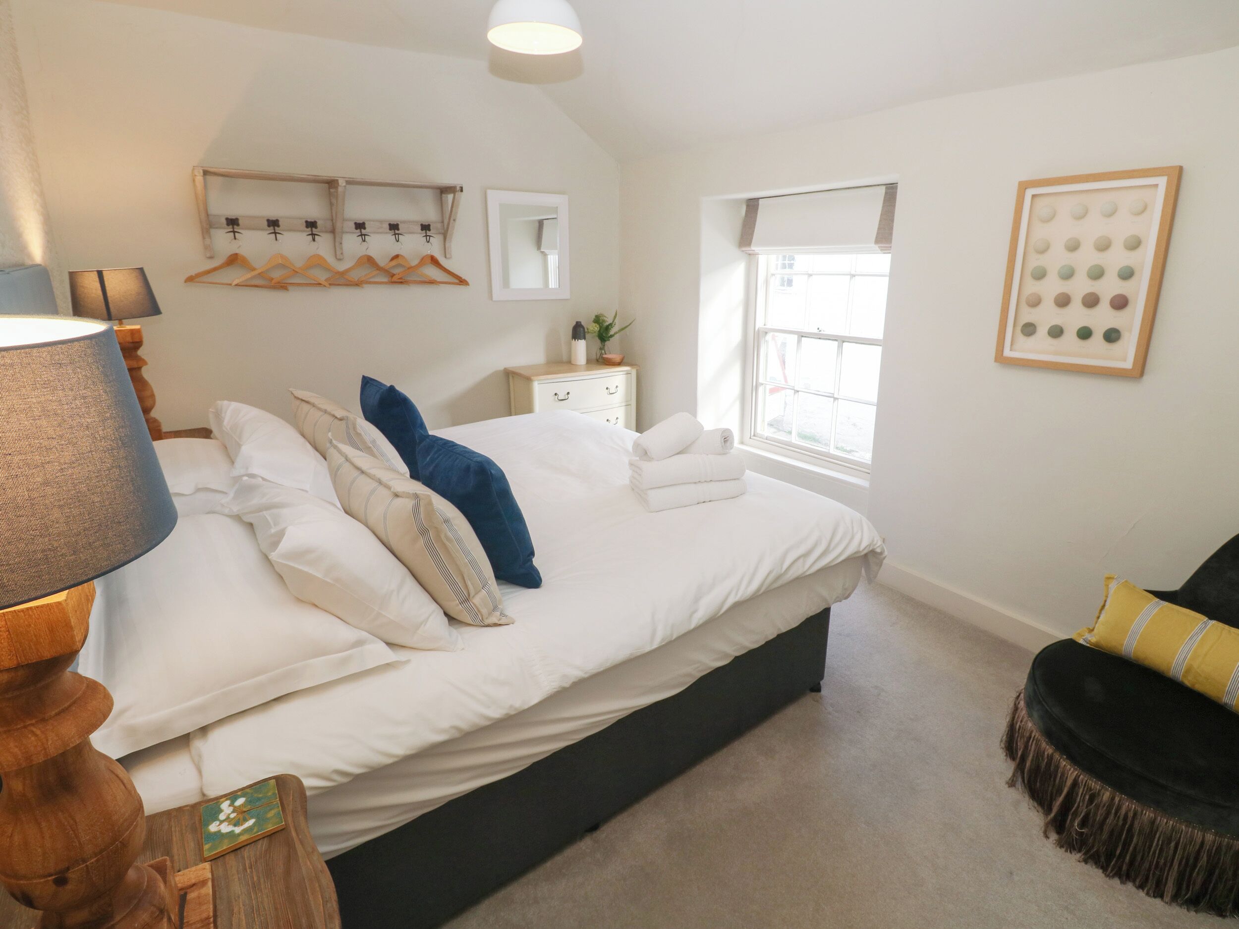 A bedroom with a bed, bedside table, lamp, and a window.