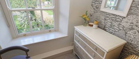 A bedroom with a window, a dresser, a chair, and a bed.