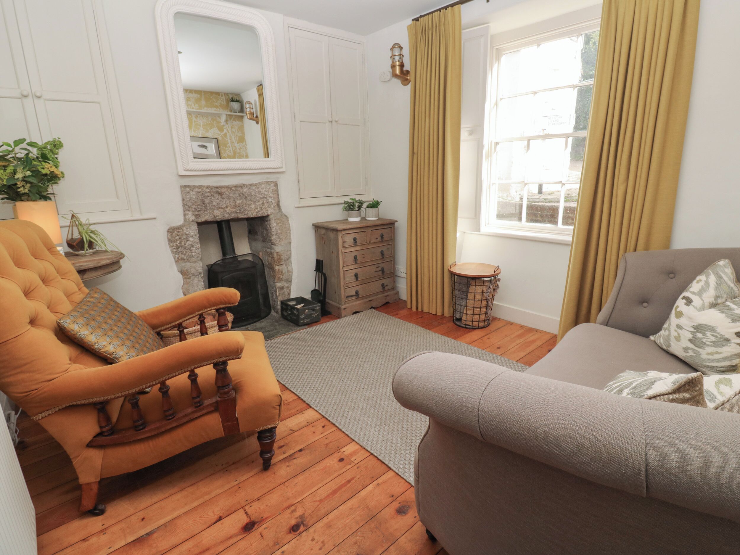 Una sala de estar acogedora con chimenea, muebles de madera y un ventanal con cortinas.