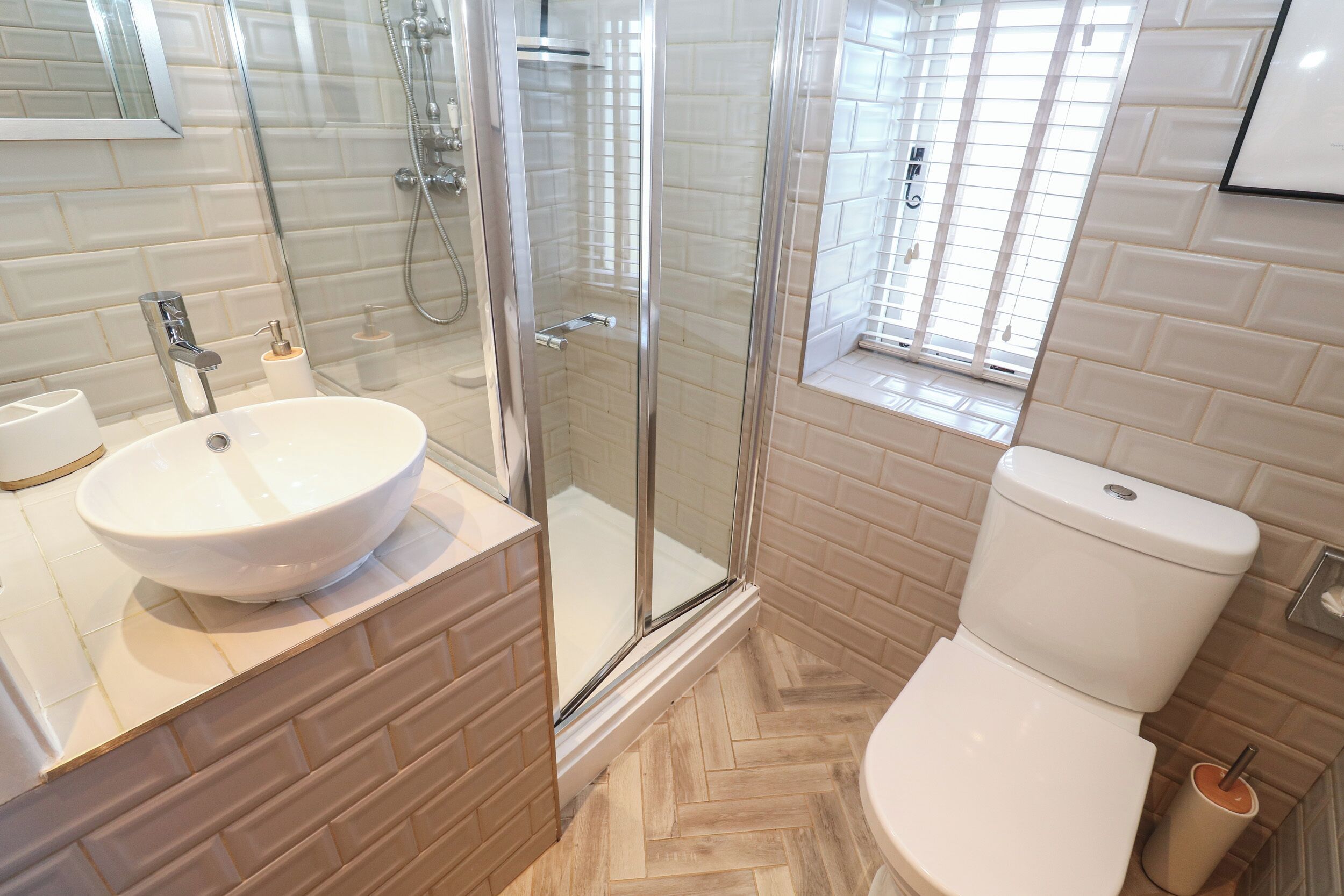 A modern bathroom with a glass shower enclosure, a white sink, and a toilet.