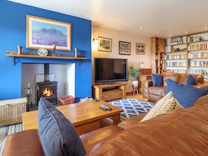 A cozy living room with a fireplace, a television, a bookshelf, and comfortable seating.