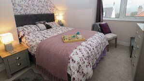A bedroom with a bed, bedside tables, a dresser, and a window with a view. - Skyelands (Wooler)