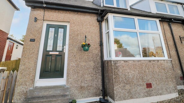 A two-story house with a green door, a small balcony, and a window. - Skyelands (Wooler)
