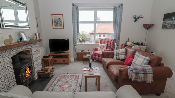 A living room with a fireplace, sofa, and television. - Skyelands (Wooler)