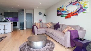 A modern living room with a grey sofa, a round coffee table, and a vibrant abstract painting on the wall.