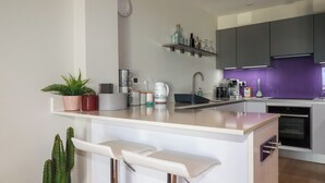 A modern kitchen with a central island, bar stools, a sink, and various appliances.