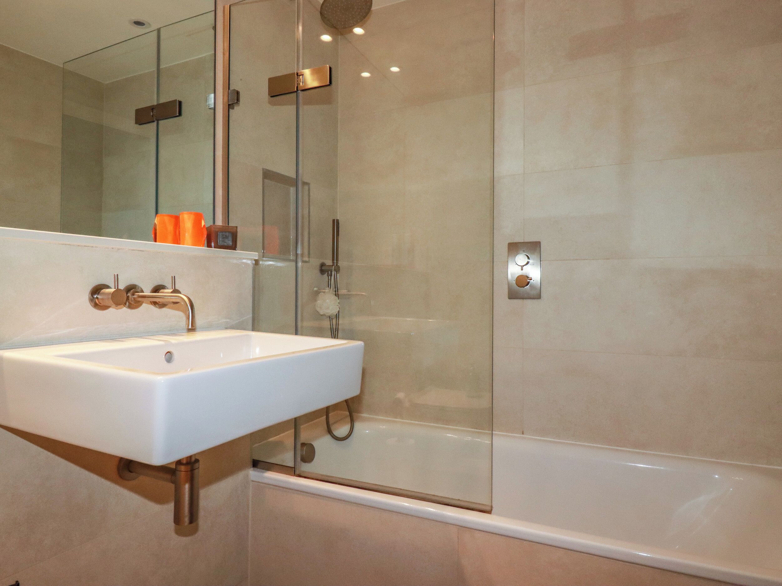 A modern bathroom with a white sink, a glass shower enclosure, and a bathtub.