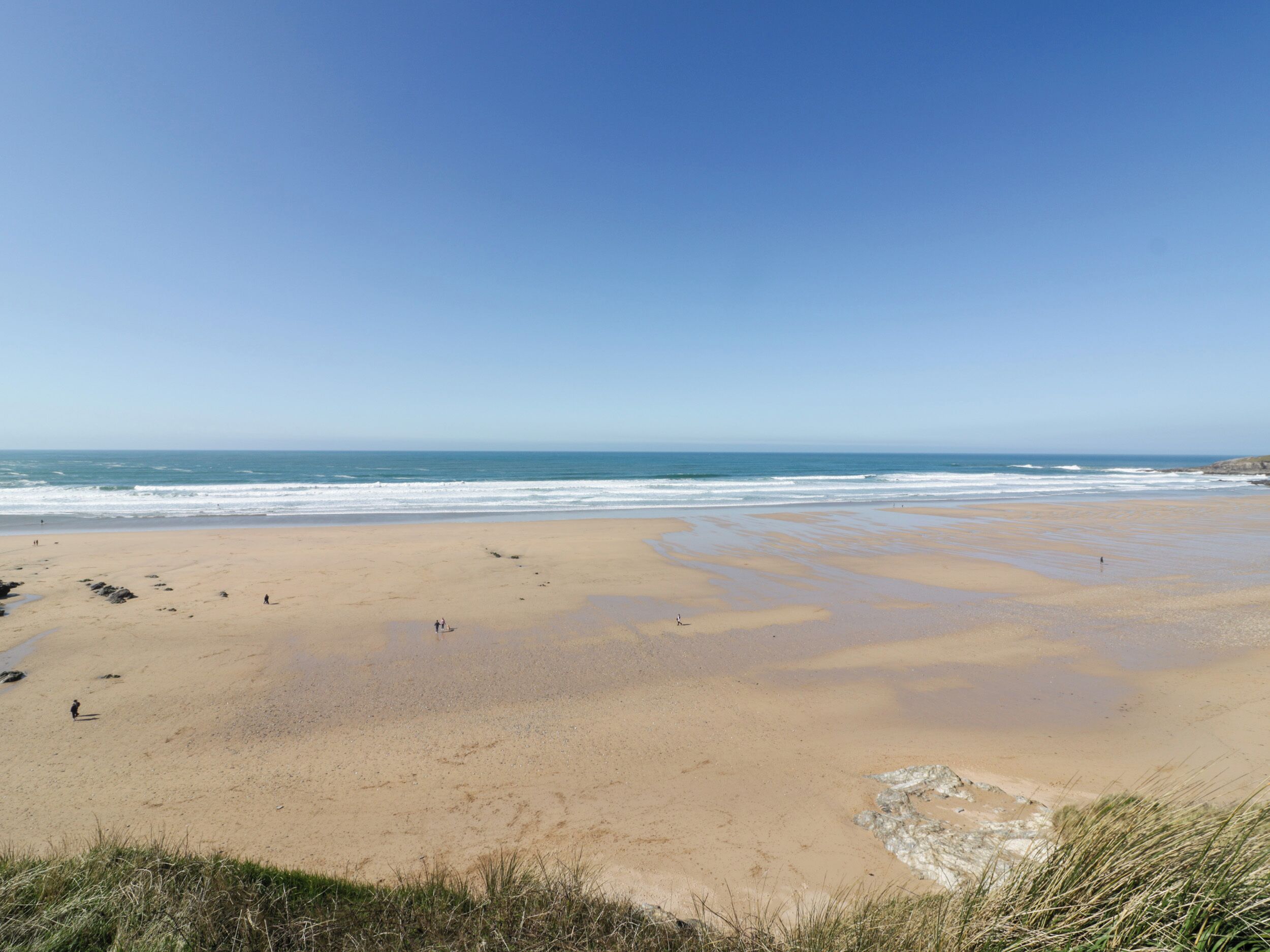 Une vaste plage de sable fin, avec des vagues douces et un ciel dégagé.
