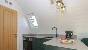 A compact kitchen with a built-in oven, a sink, and a coffee maker. - Leadon View Willow (Newent)