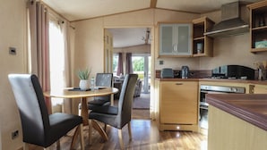 A compact kitchen with a dining area, wooden cabinets, a stove, and a small table with chairs. - Ashcroft (Preston)
