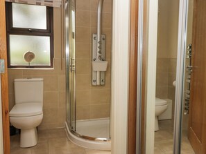 Un baño con ducha de vidrio, inodoro y ventana con vidrio esmerilado.