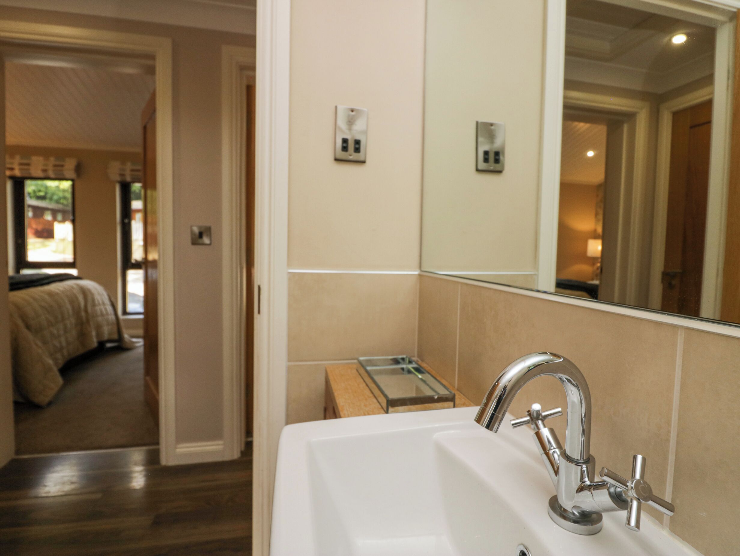 A bathroom with a sink, mirror, and a small window.