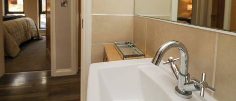 A bathroom with a sink, mirror, and a small window.