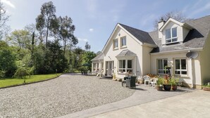 A two-story house with a gravel driveway, outdoor seating area, and potted plants. - Mill House (Moville)