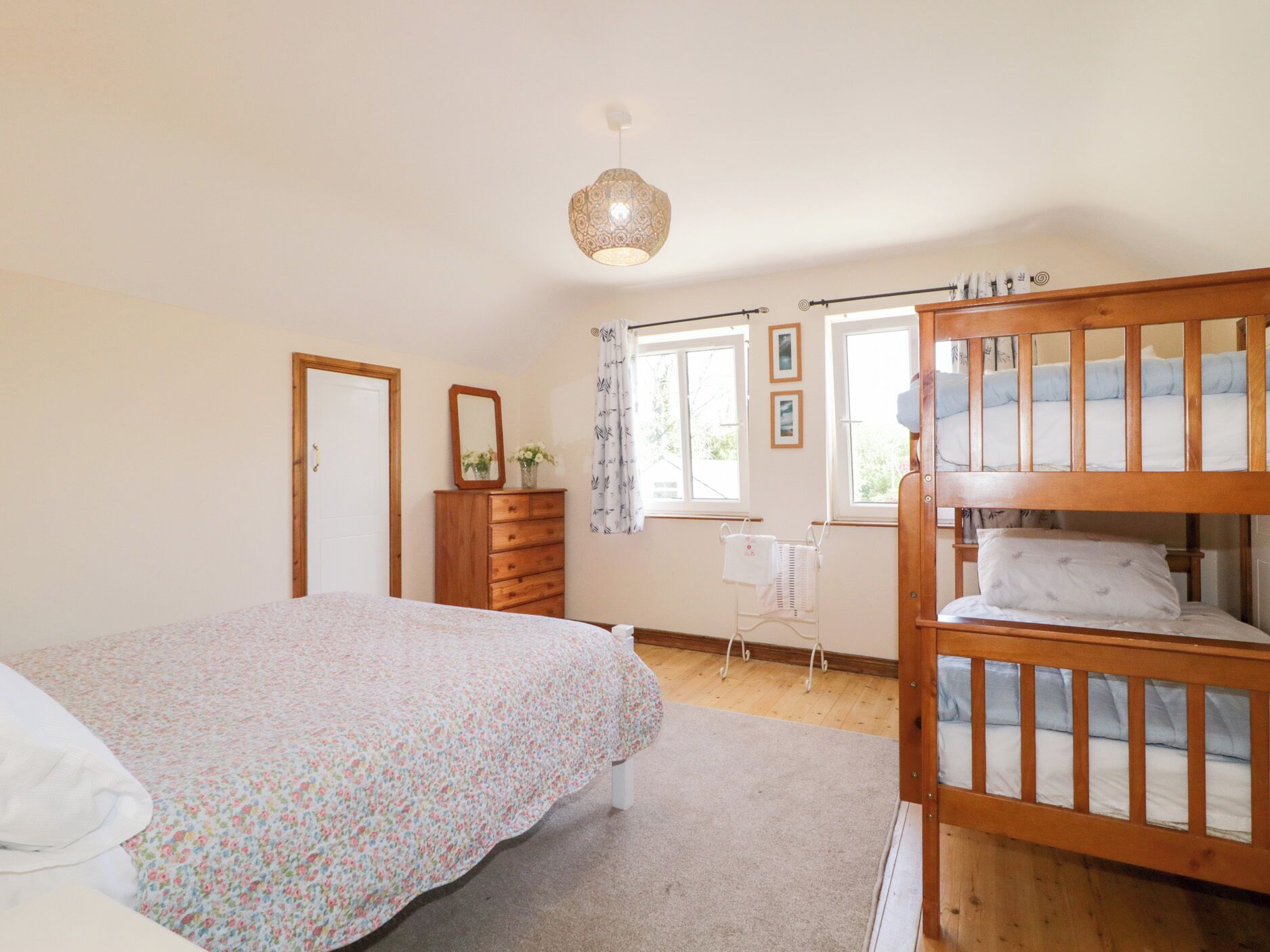 A bedroom with a bunk bed, a dresser, a mirror, and a window with curtains.