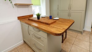 Una cocina con encimera de madera, una planta en maceta, una taza azul y un plato blanco.
