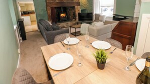 Una sala de estar acogedora con chimenea, un comedor con mesa para cuatro, y un sofá.