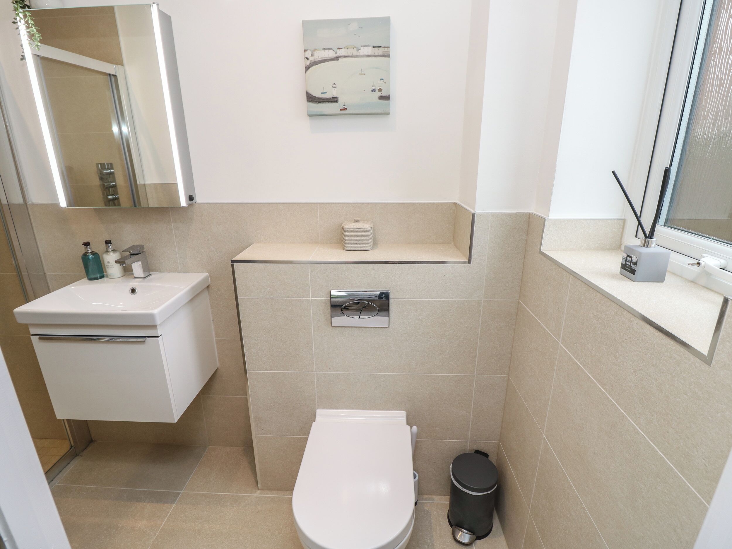 A small bathroom with a toilet, sink, and mirror.